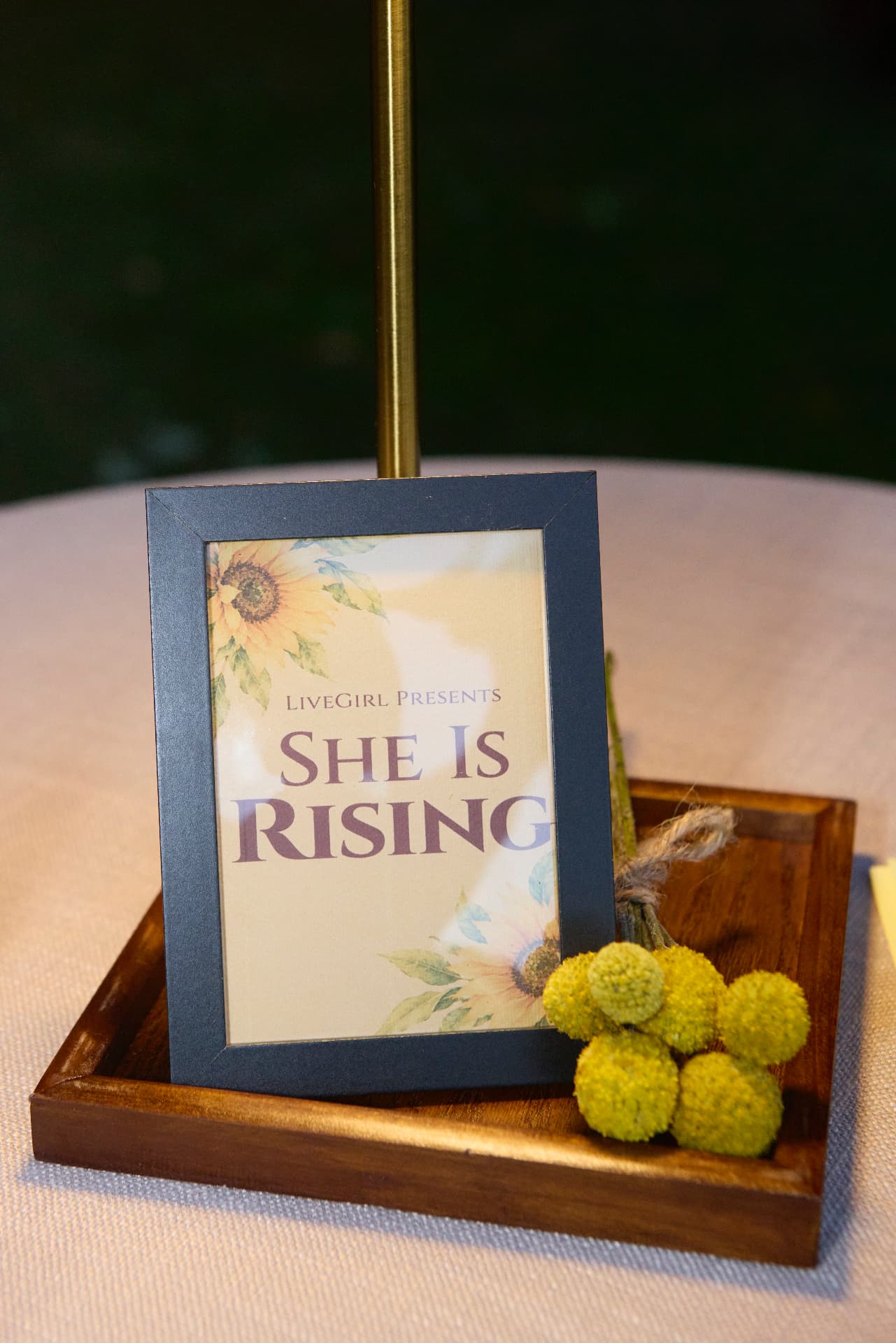 A She Is Rising table sign with billy buttons