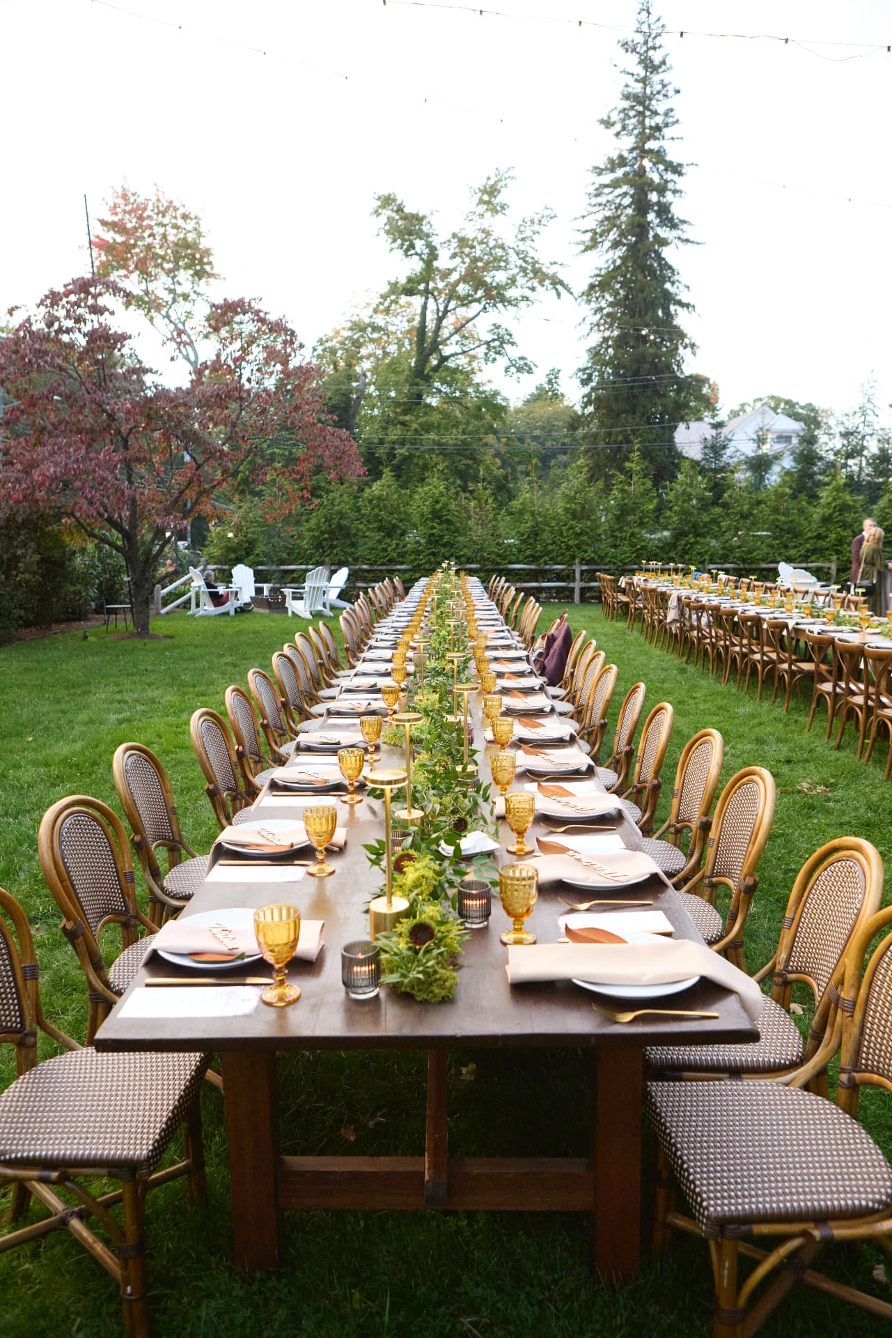 A long garden table set beneath autumn trees