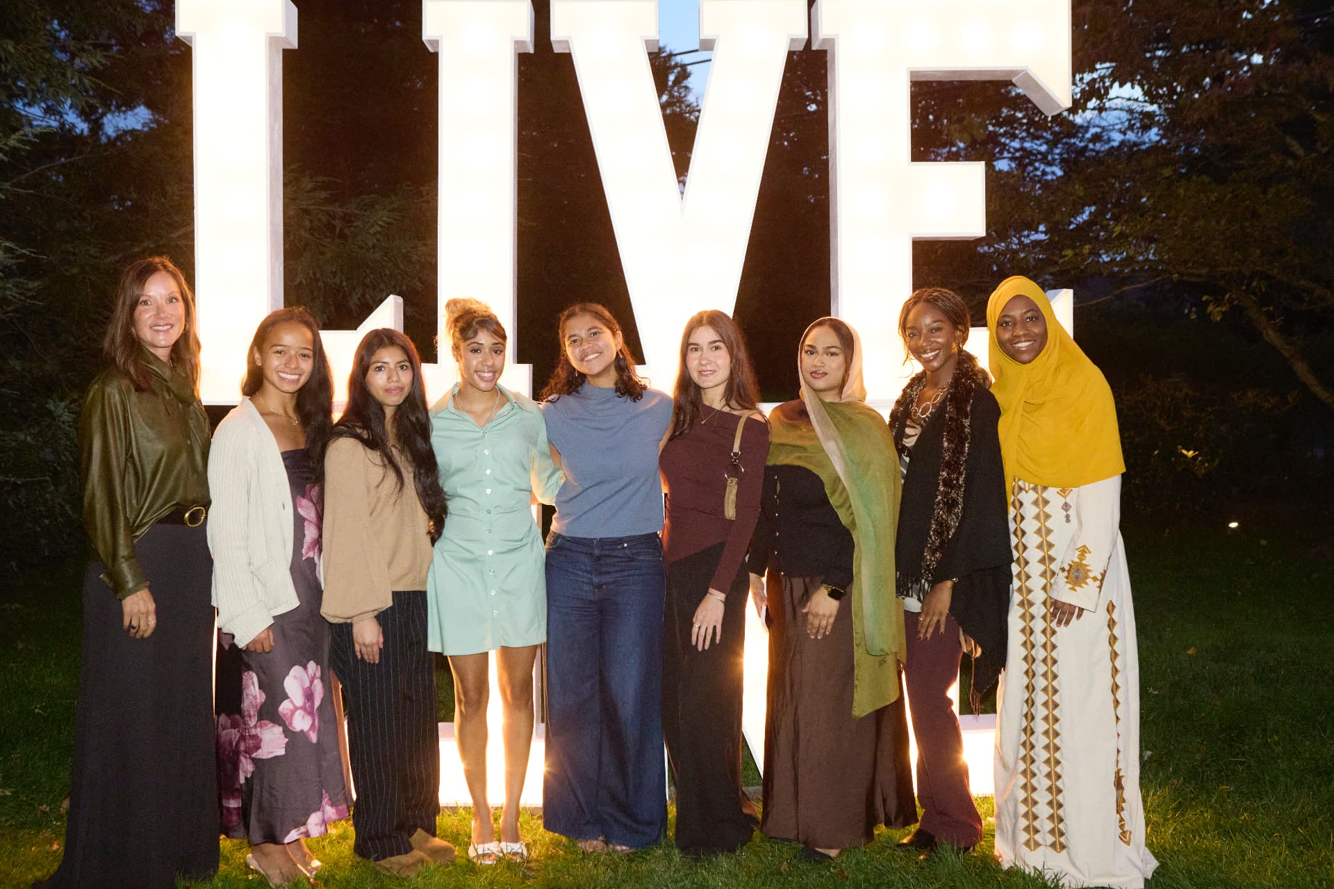 Young women together before the glowing LiveGirl letters