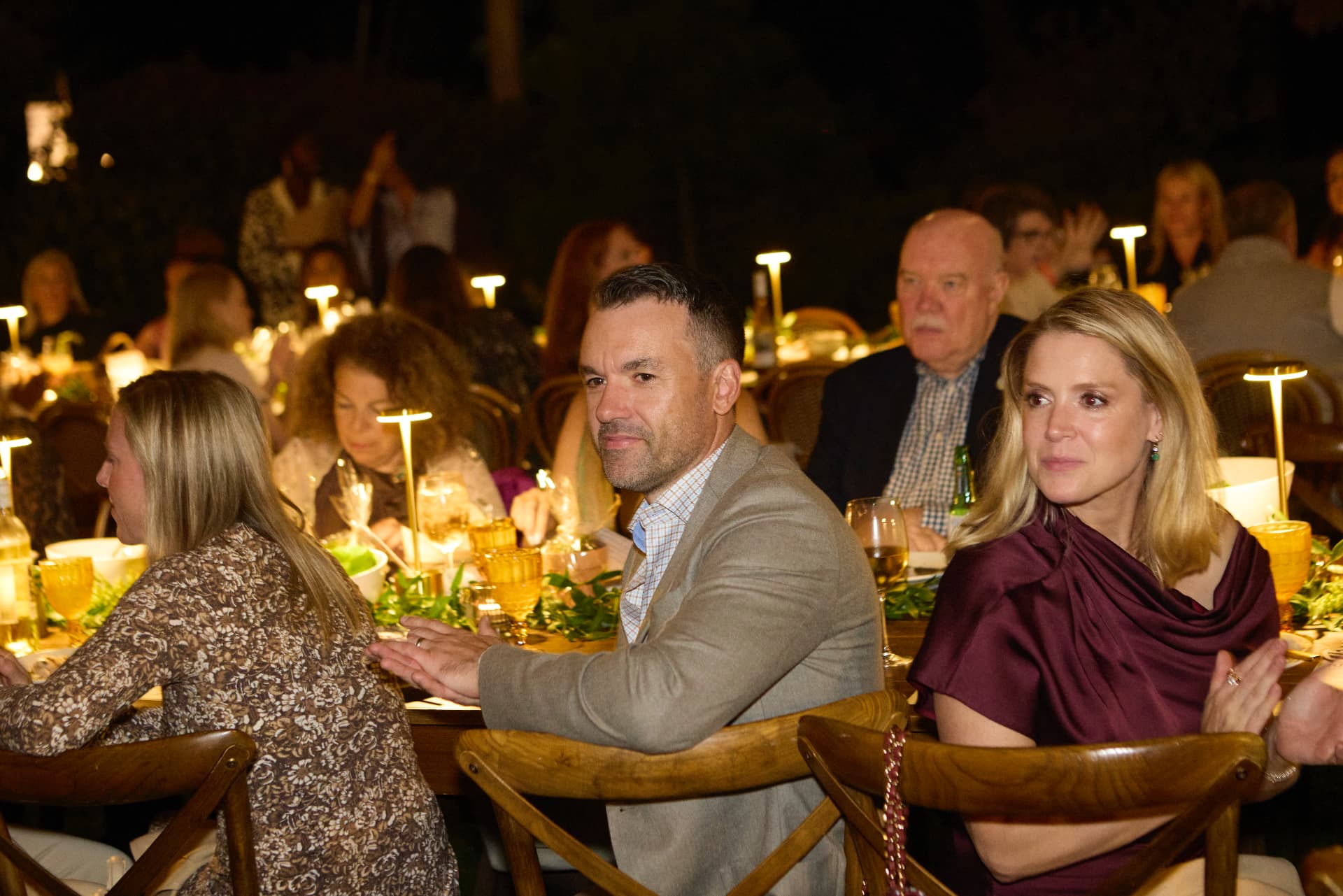 Guests sharing a candlelit table beneath the trees