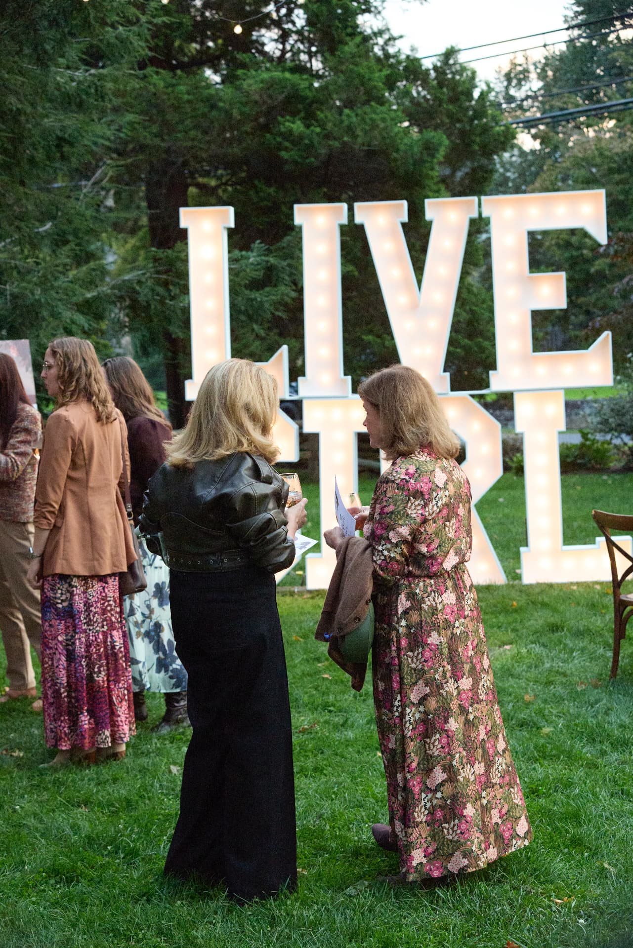 Guests gathering on the lawn beneath the glowing LiveGirl letters