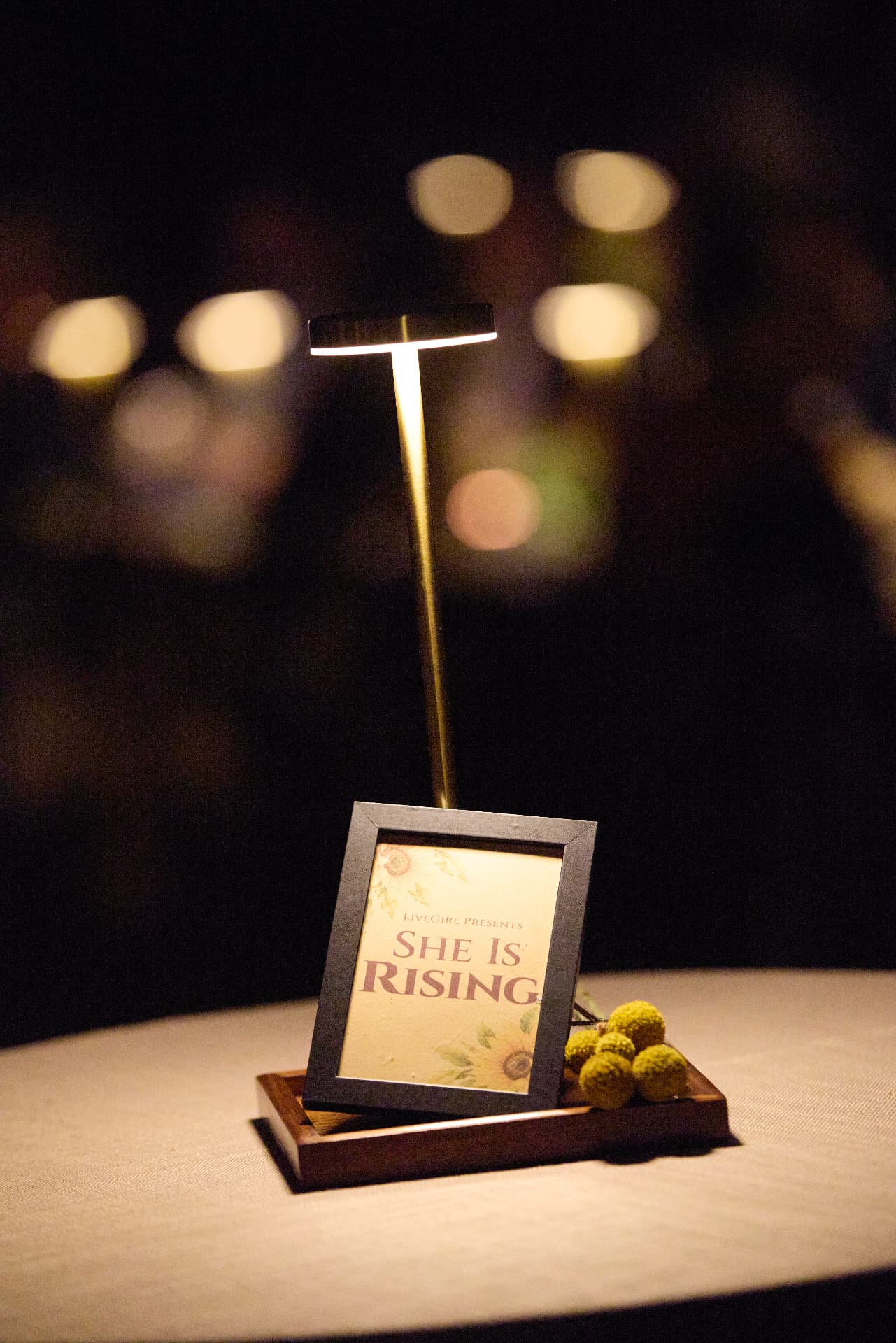 A She Is Rising table sign glowing at night